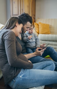 Parents with son using digital tablet while sitting in living room at home