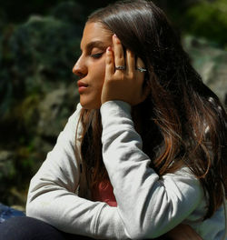 Young woman with eyes closed sitting outdoors