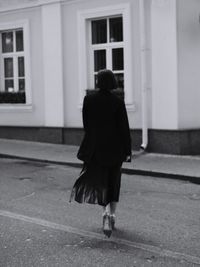 Rear view of woman walking on street against building