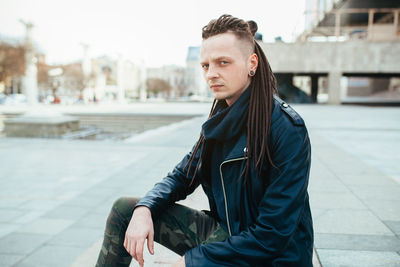 Portrait of serious hipster sitting at terrace in city