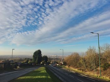 Road by trees against sky