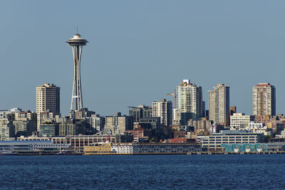 Sea by cityscape against clear sky