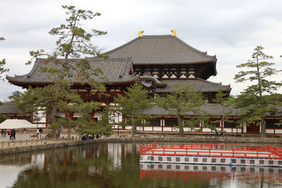 Built structure by lake and buildings against sky