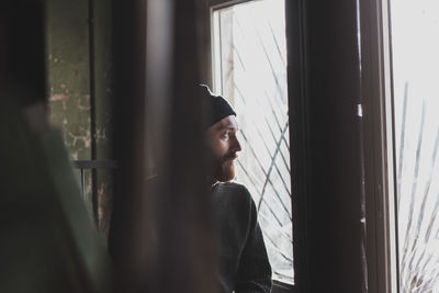 Portrait of young man looking through window