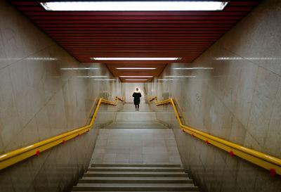 Rear view of man walking on staircase
