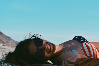 Woman lying against clear sky