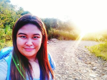 Portrait of smiling young woman standing against plants