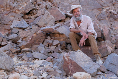 Senior man sitting on rock in the desert 