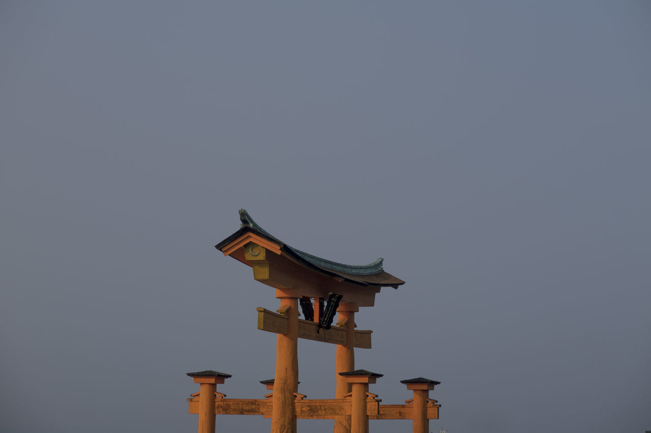 LOW ANGLE VIEW OF BIRD ON BIRDHOUSE AGAINST CLEAR SKY