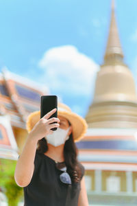 Midsection of man using smart phone against building