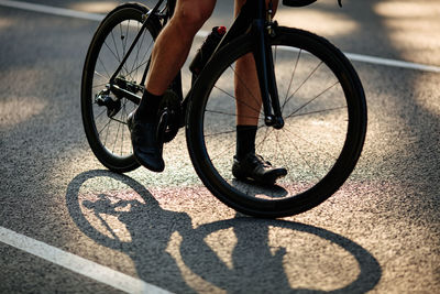 Close up of strong male legs in sport sneakers actively riding bike on asphalt road. 