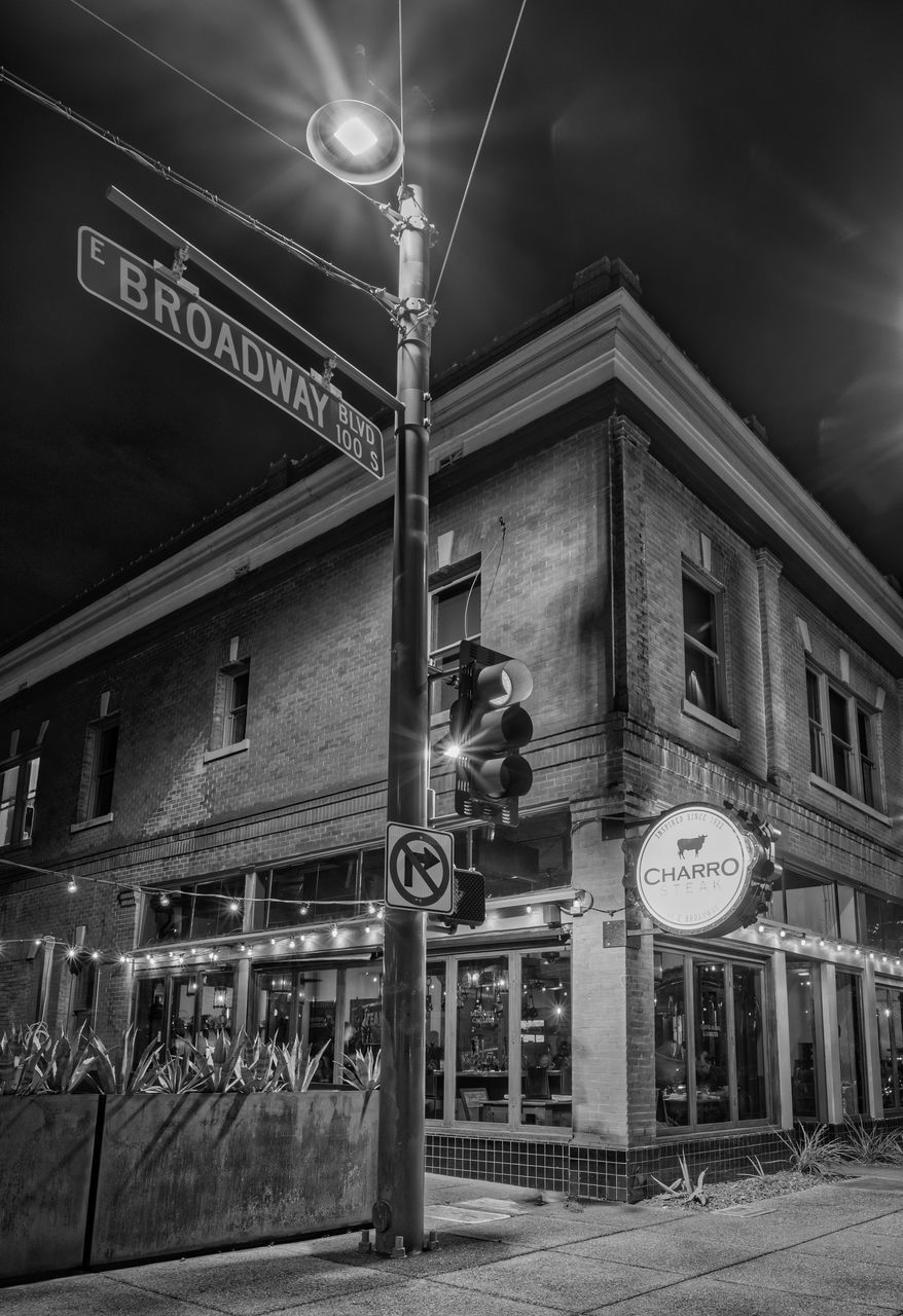 ILLUMINATED STREET LIGHT BY BUILDING AT NIGHT