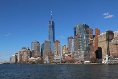 City at waterfront against blue sky