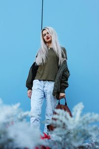 Low angle view of young woman against blue sky