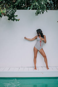 Full length of woman standing by swimming pool