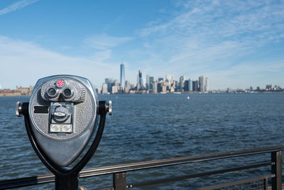 Coin-operated binocular by river in city