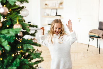 Smiling girl with christmas tree at home