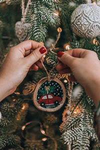 Cropped hand of woman decorating christmas tree