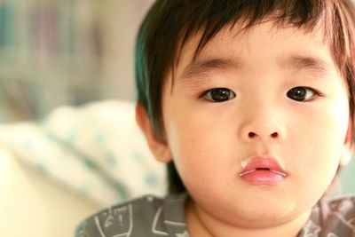 Close-up portrait of cute boy with milk on lips at home