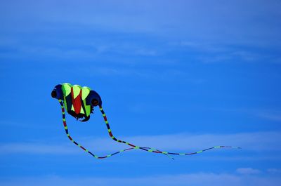 Low angle view of kites flying against blue sky