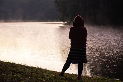 Woman standing on the lawn and mist floating over  water at pang tong reservoir in mae hong son.