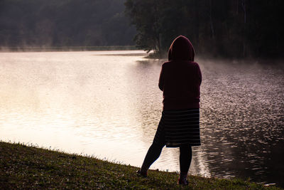 Rear view of woman standing at lakeshore