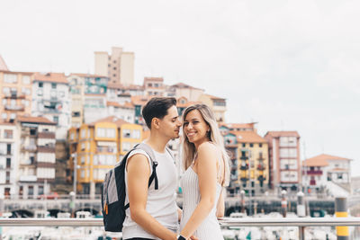 Couple embracing while standing against cityscape