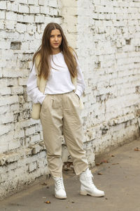 Portrait of teenage girl standing against brick wall