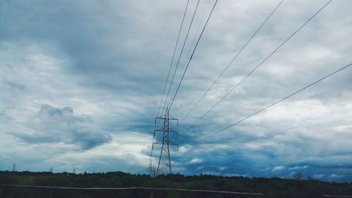 Low angle view of electricity pylon against cloudy sky