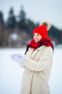 Portrait of smiling young woman standing on snow