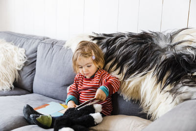 Full length of cute baby girl sitting on sofa at home