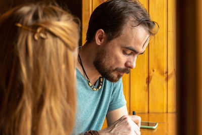 Young man having dinner in little cafe while sitting at the table near window