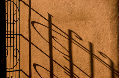 Shadow of fence on brown wall
