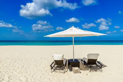 Deck chairs on beach against blue sky