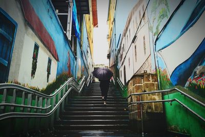 Rear view of man walking on staircase