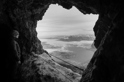 Man standing by cave looking at scenic view