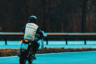 Rear view of man riding motorcycle on road