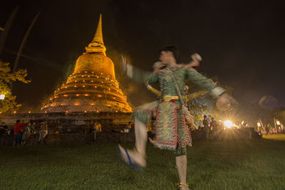 Blurred motion of illuminated temple against sky at night