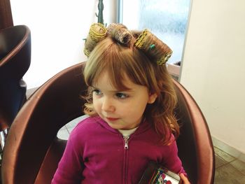 High angle view of girl with hair curlers sitting on chair at salon