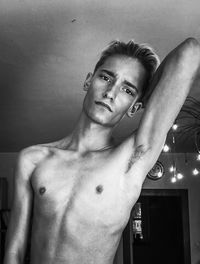 Low angle portrait of shirtless young man standing at home