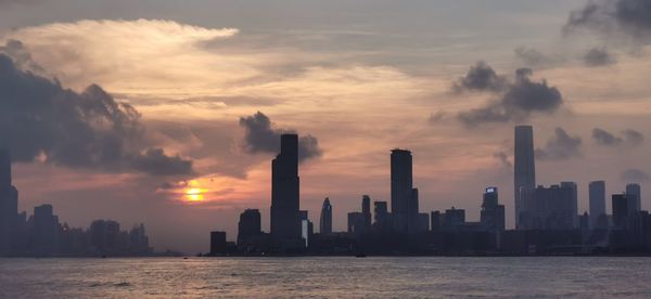 Scenic view of sea by buildings against sky during sunset