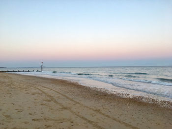 Scenic view of beach against clear sky during sunset