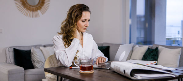 Young woman using mobile phone while sitting at home