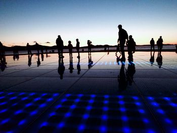 Silhouette people walking on tiled floor against clear sky - salutation to the sun in zadar croatia