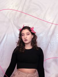 Portrait of beautiful young woman standing on bed