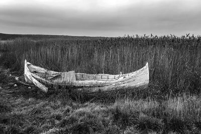 Abandoned ship on field against sky