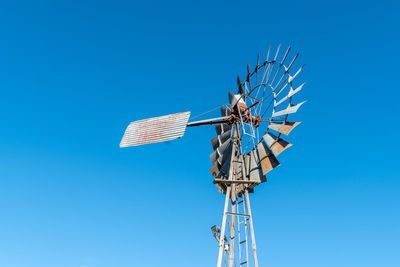 Low angle view of windmill against clear blue sky