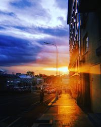 Cars on street in city against sky at sunset