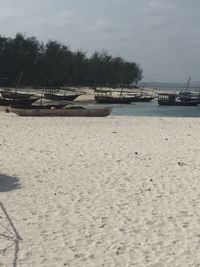 Boats moored on beach against sky