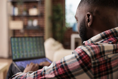 Side view of man using mobile phone at home